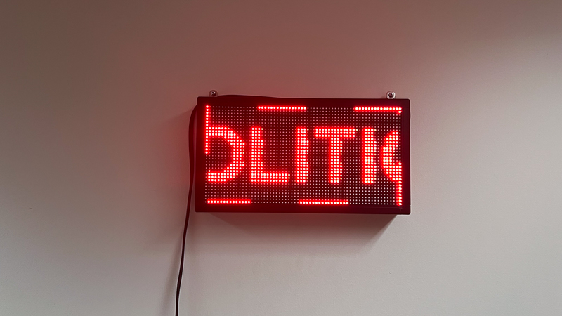 A red LED sign that reads 'Politics' in a continuous loop.