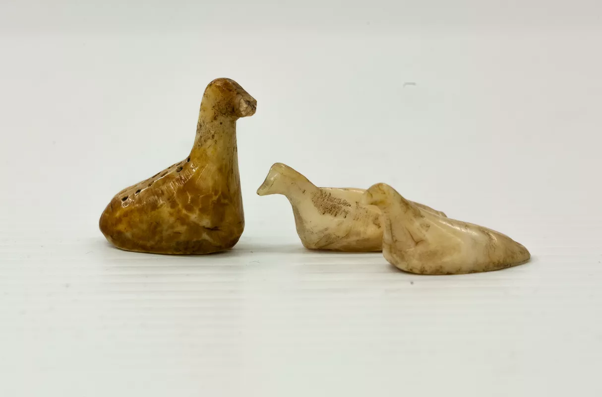 Three small ivory carvings of birds, one of which has black pigment details.