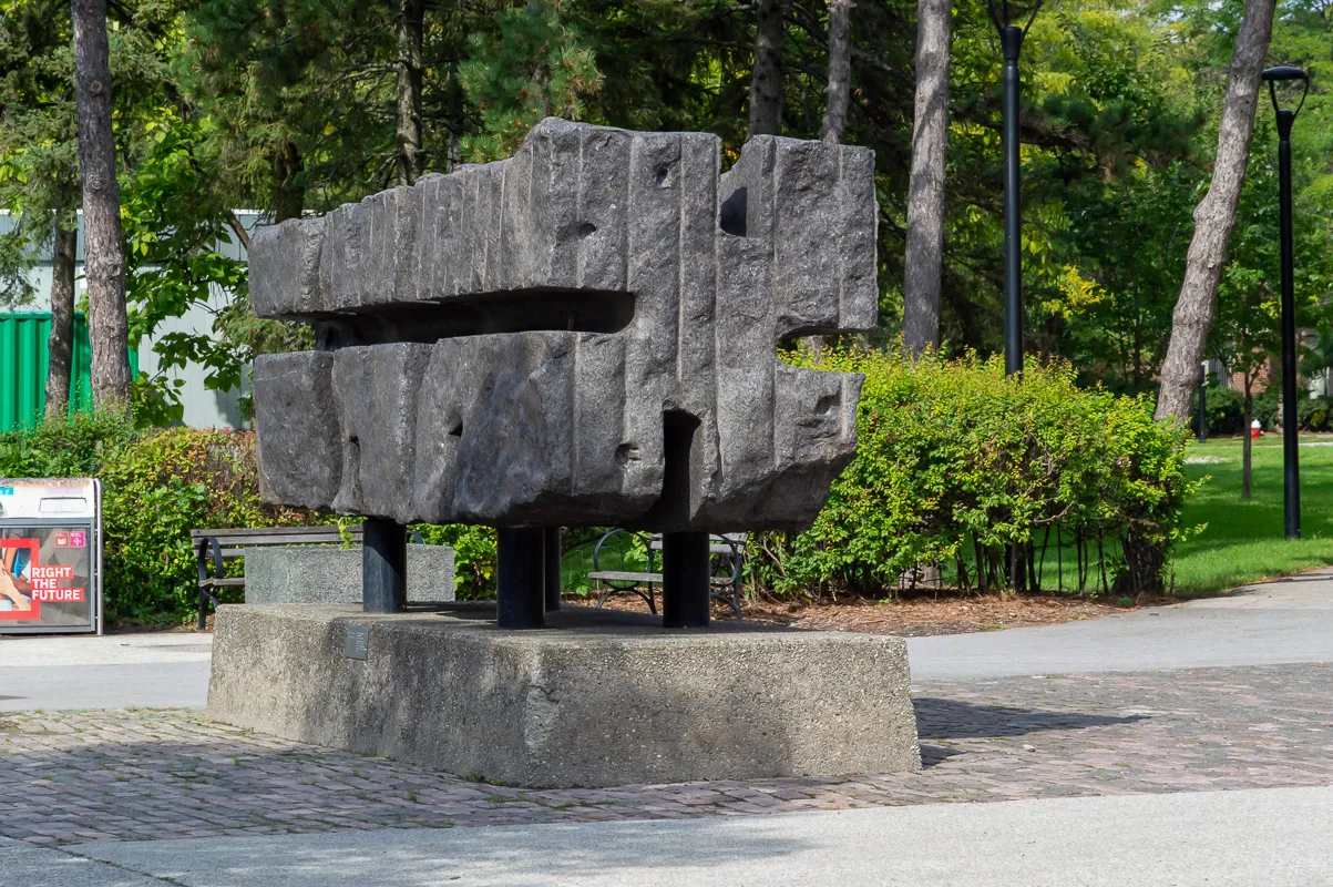 Large chiselled granite sculpture which resembles an extruded form.