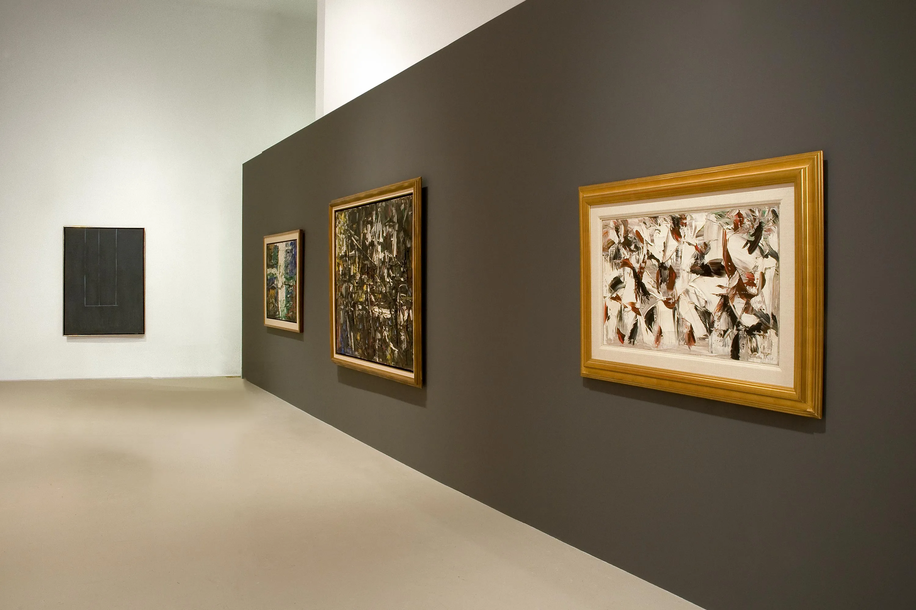 An art exhibition with black and white walls displaying abstract art
