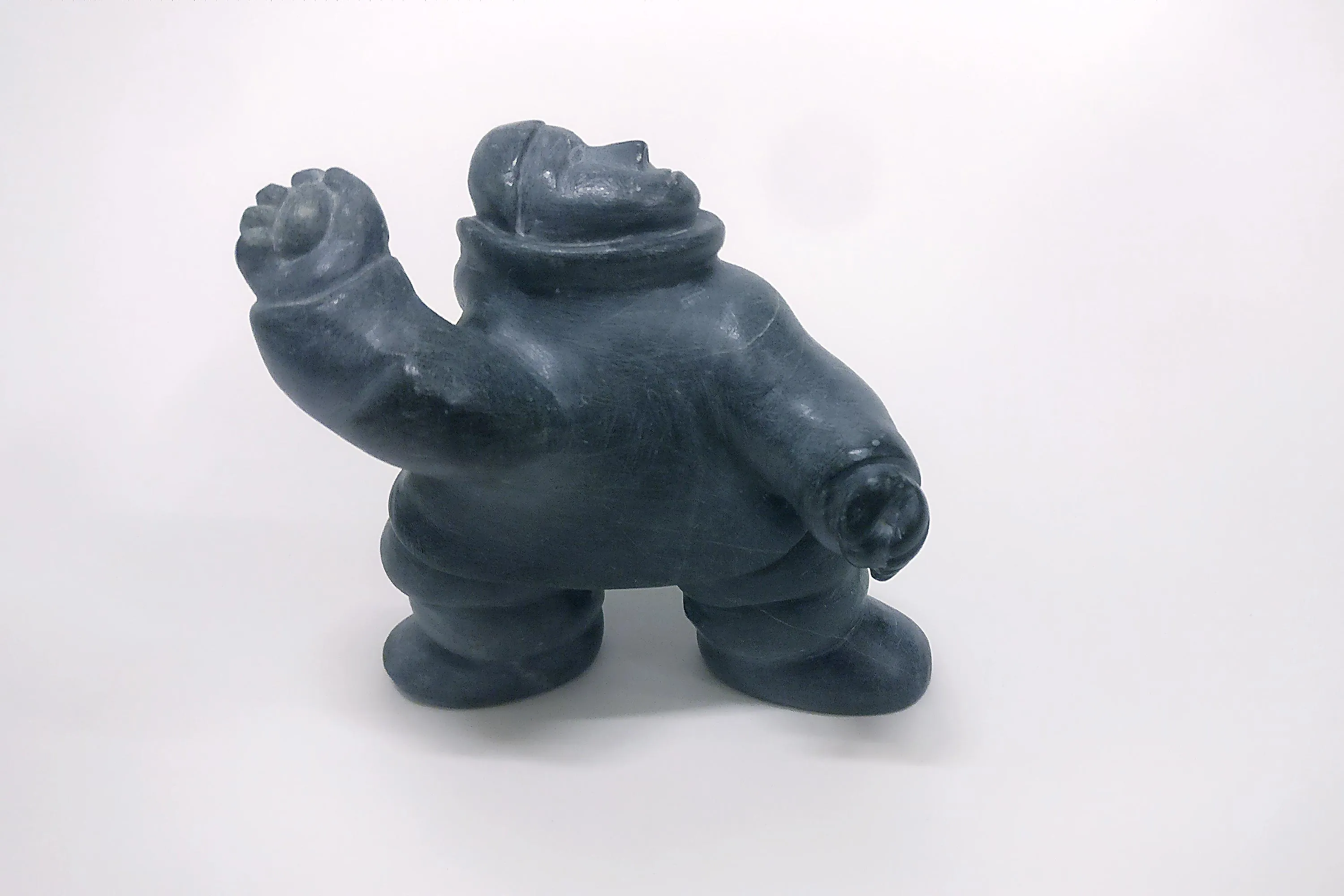 Dark stone statue of a person raising their right hand