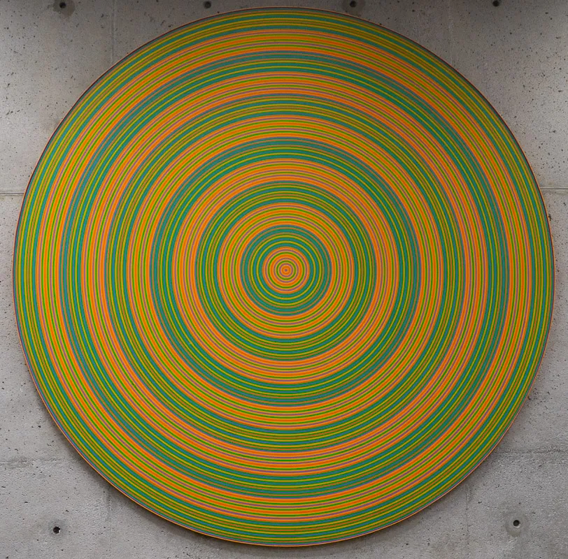 Concentric circle of green and yellow stripes on a round canvas support.