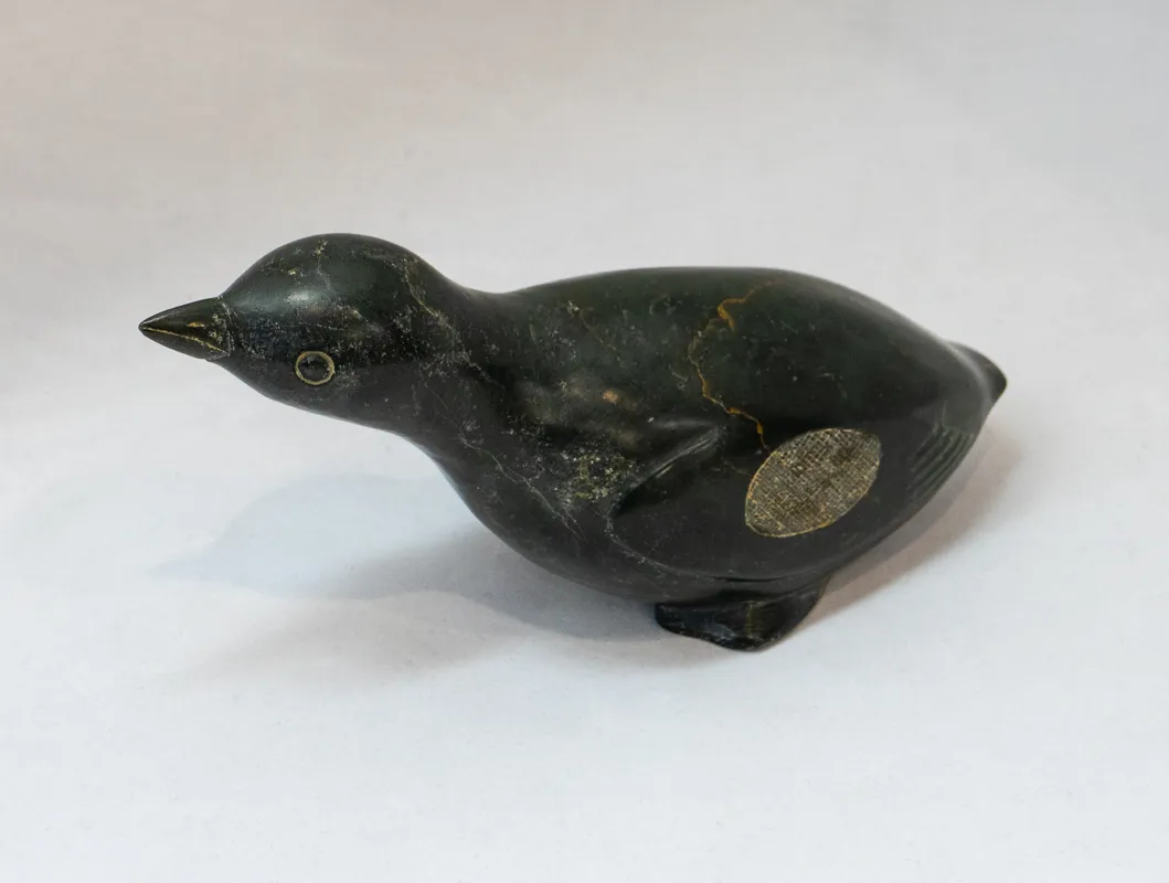 Dark stone carved bird with pointy beak. 