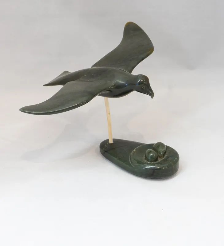 Bird flying above nest with eggs in green stone.