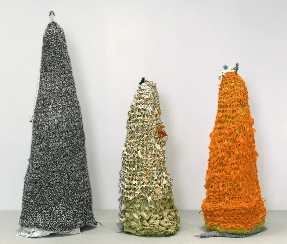 Three crocheted structures, vaguely hill shaped.