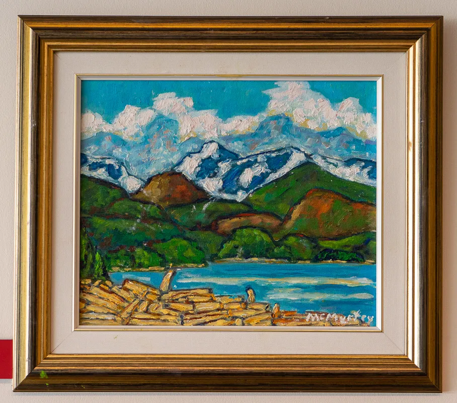Logs floating in water in front of a mountain view.