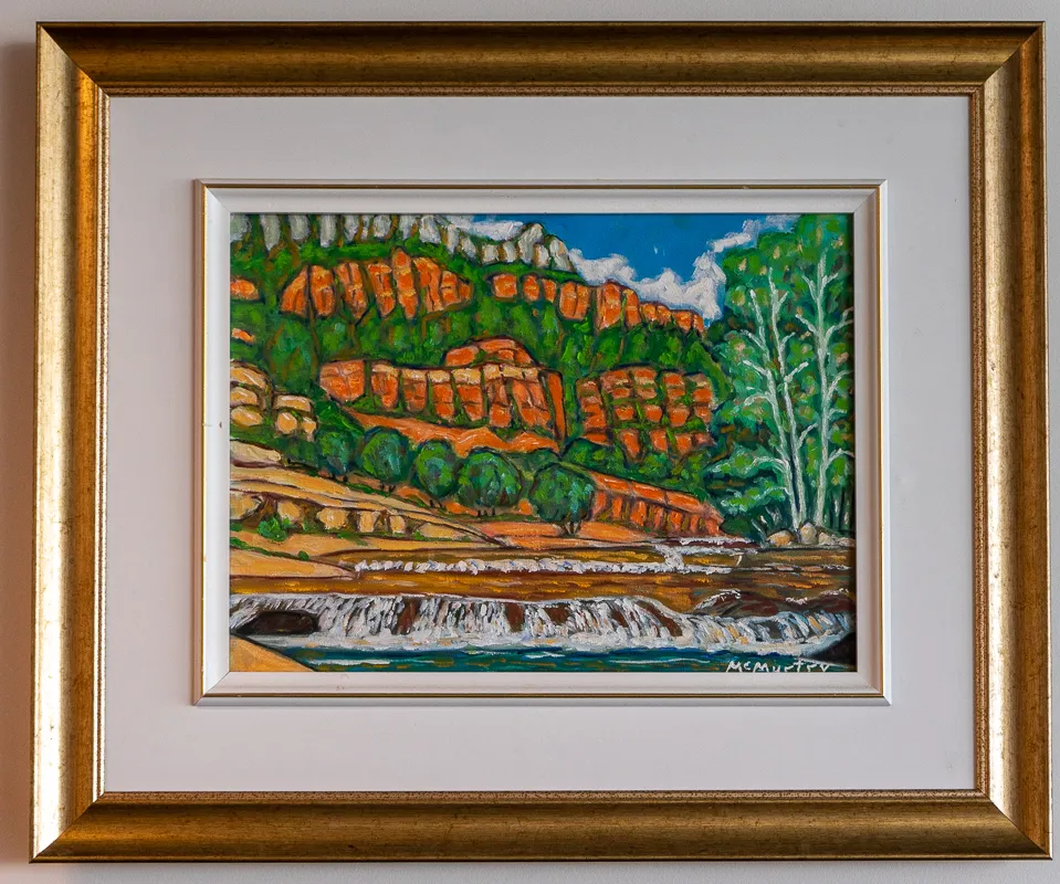 Side of a cliff face in greens, reds, and yellows.