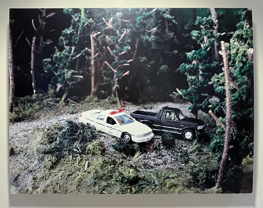 OPP police car and black pickup truck parked in a forest clearing. Appears to be a photograph of a model.
