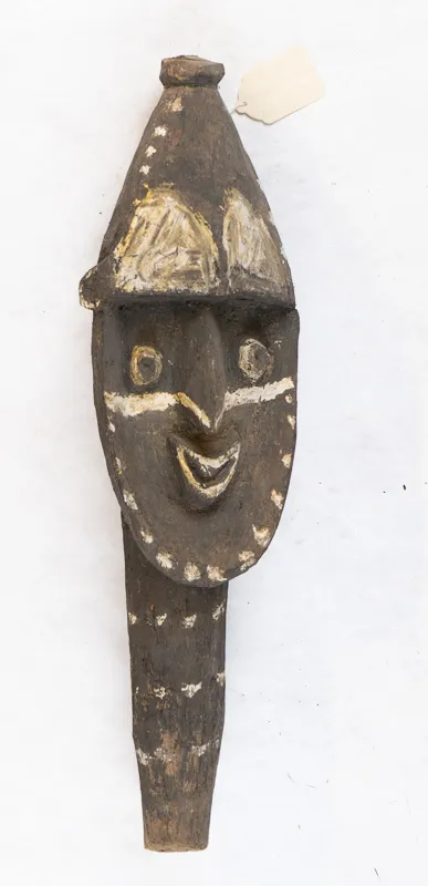 Digging stick with face carved into it. 