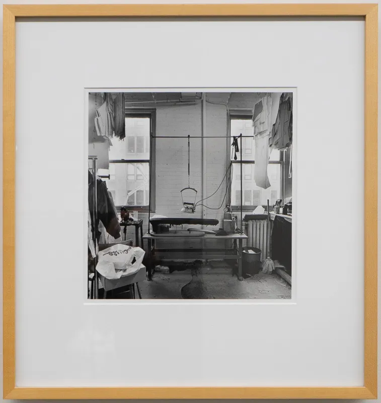 Sweatshop with sewing machine in black and white photograph.