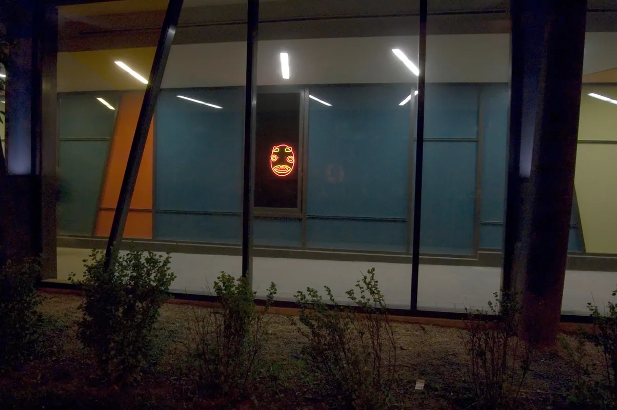 Neon sign in the shape of an African mask in a corridor on the campus.