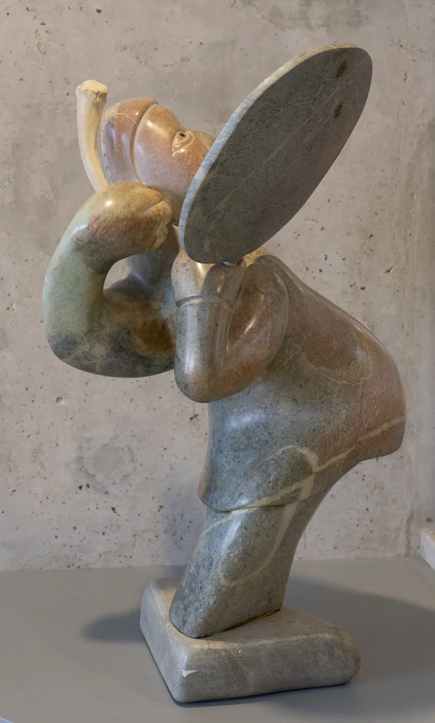 Distorted figure holding drum and beater.