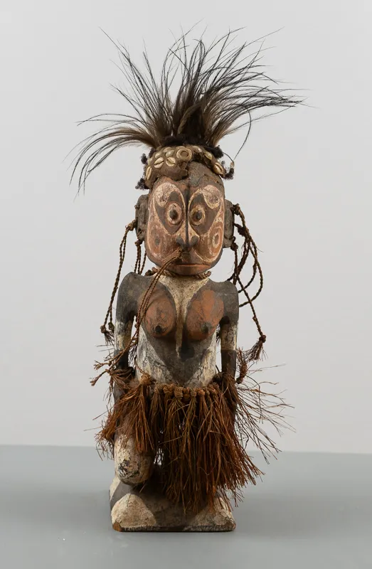 Short carved human figure with feathered headwear.
