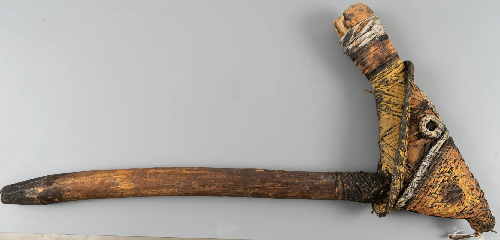 Axe made with rattan and wood with geometric markings.