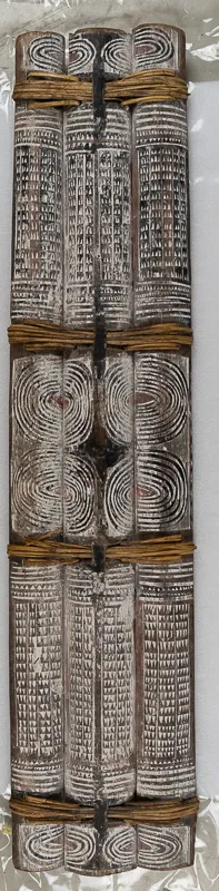 Three decorated split logs fastened together into a shield with rattan.