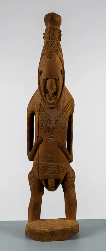 Stylized sculpture of standing figure with legs wide apart. 