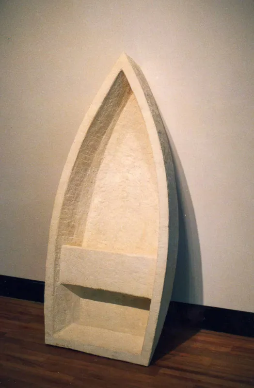 A simplified shallow fishing skip in stone leaning against a wall.