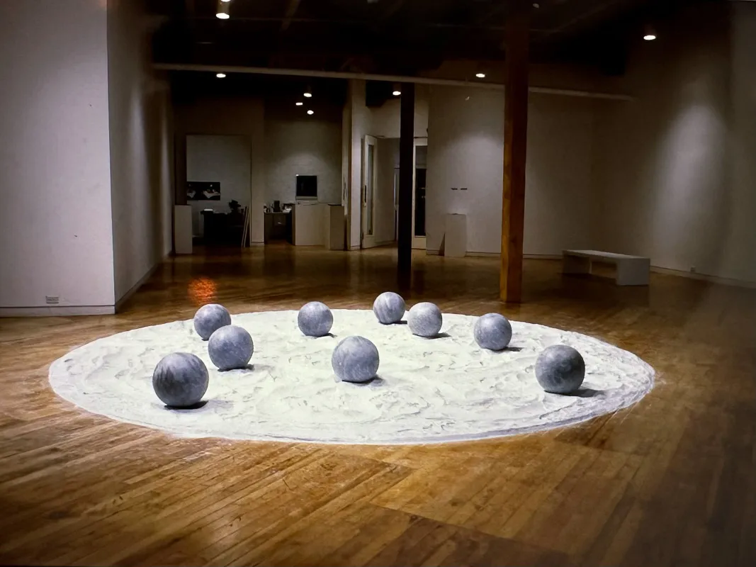 A group of stone spheres, about bowling ball size, on a circular field of talc.